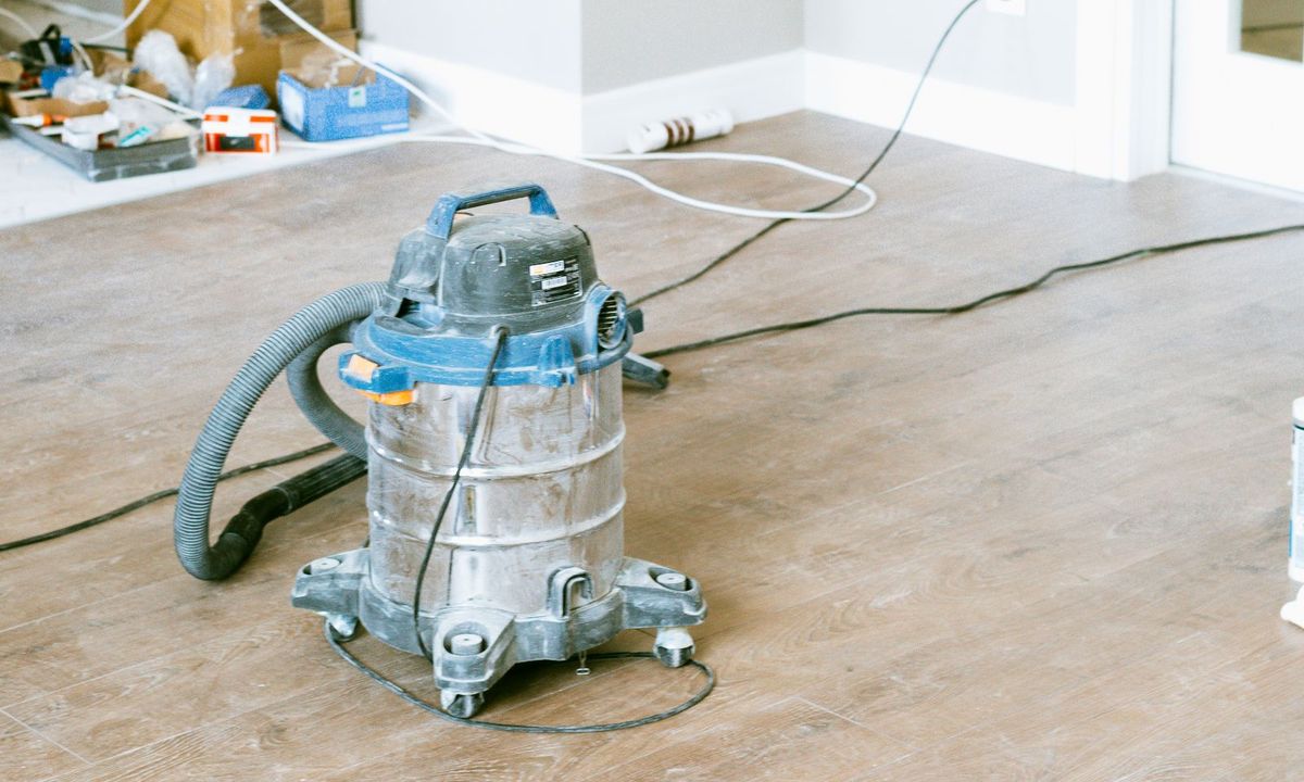 Shop vacuum on the floor of a freshly renovated room, construction dust and cords still down (stock photo)