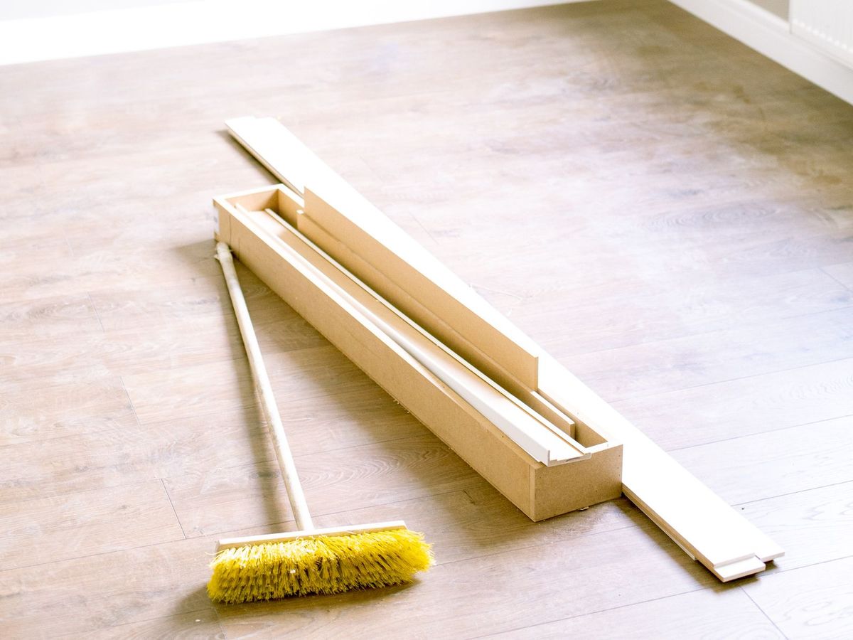 Empty renovated room with trim boards and a push broom, before the post-construction clean (stock photo)