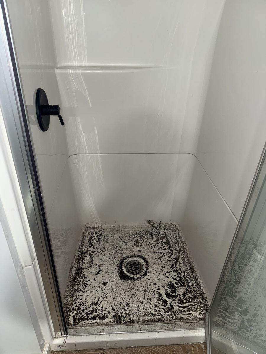 Shower base darkened by buildup before cleaning